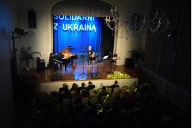 Zdjęcie przedstawia scenę z dużym napisem "SOLIDARNI Z UKRAINĄ" w sali widowiskowej Domu Narodowego w Cieszynie