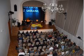 Zdjęcie przedstawia scenę z dużym napisem "SOLIDARNI Z UKRAINĄ" w sali widowiskowej Domu Narodowego w Cieszynie