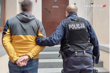 Zatrzymanie 29 -latka. Policjant trzyma za rękę zatrzymanego, który ma na rękach kajdanki. fot. KPP Cieszyn