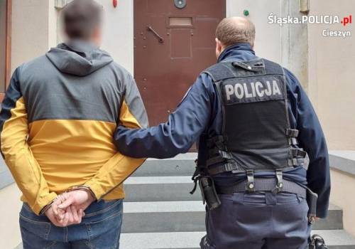 Zatrzymanie 29 -latka. Policjant trzyma za rękę zatrzymanego, który ma na rękach kajdanki. fot. KPP Cieszyn