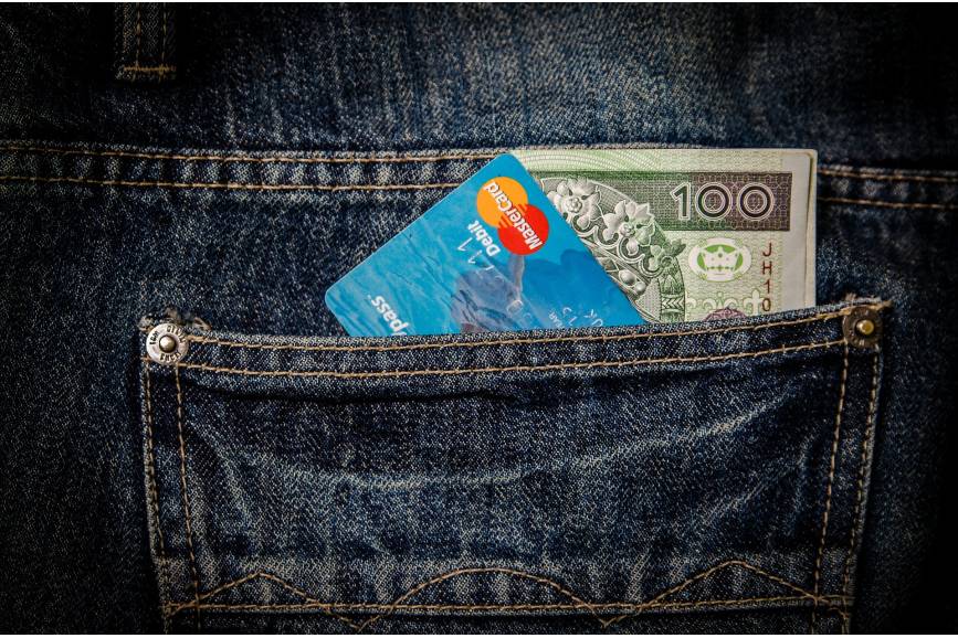 Zdjęcie przedstawia kartę kredytową oraz banknot 100 złotowy wystające z tylnej kieszeni spodni 