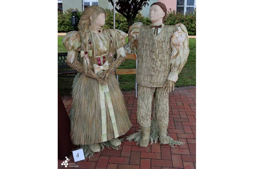 Zdjęcie przedstawia wieniec dożynkowy w kształcie kobiety i mężczyzny ubranych w stroje ludowe