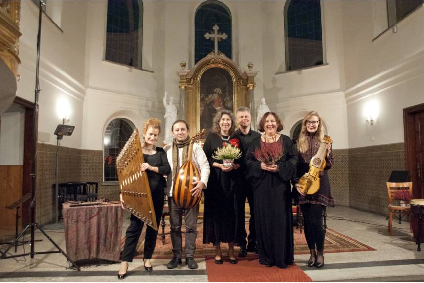 Na zdjęciu zespół z kwiatami i instrumentami. W tle ołtarz kościoła