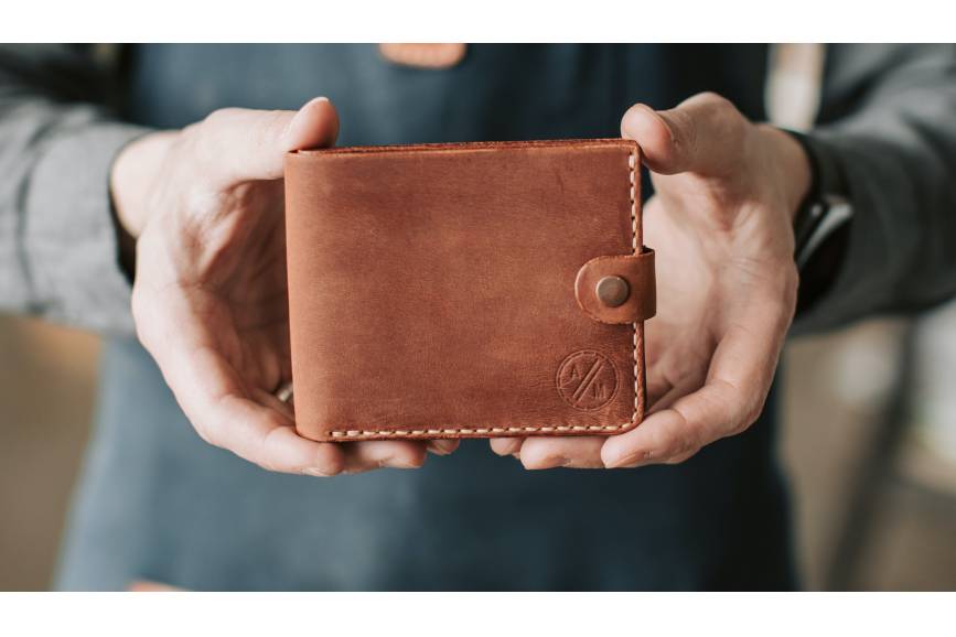 Zdjęcie przedstawia portfel trzymany w obu dłoniach