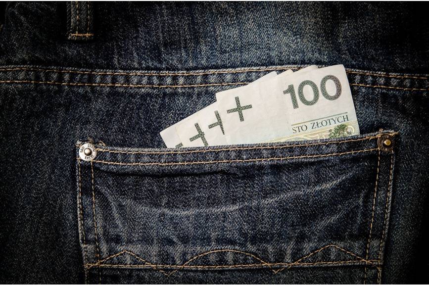 trzy stuzłotowe banknoty włożone w tylną kieszeń spodni
