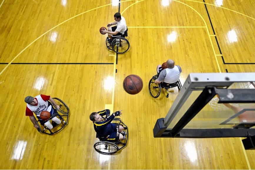 Mężczyźni na wózkach grają w koszykówkę. 